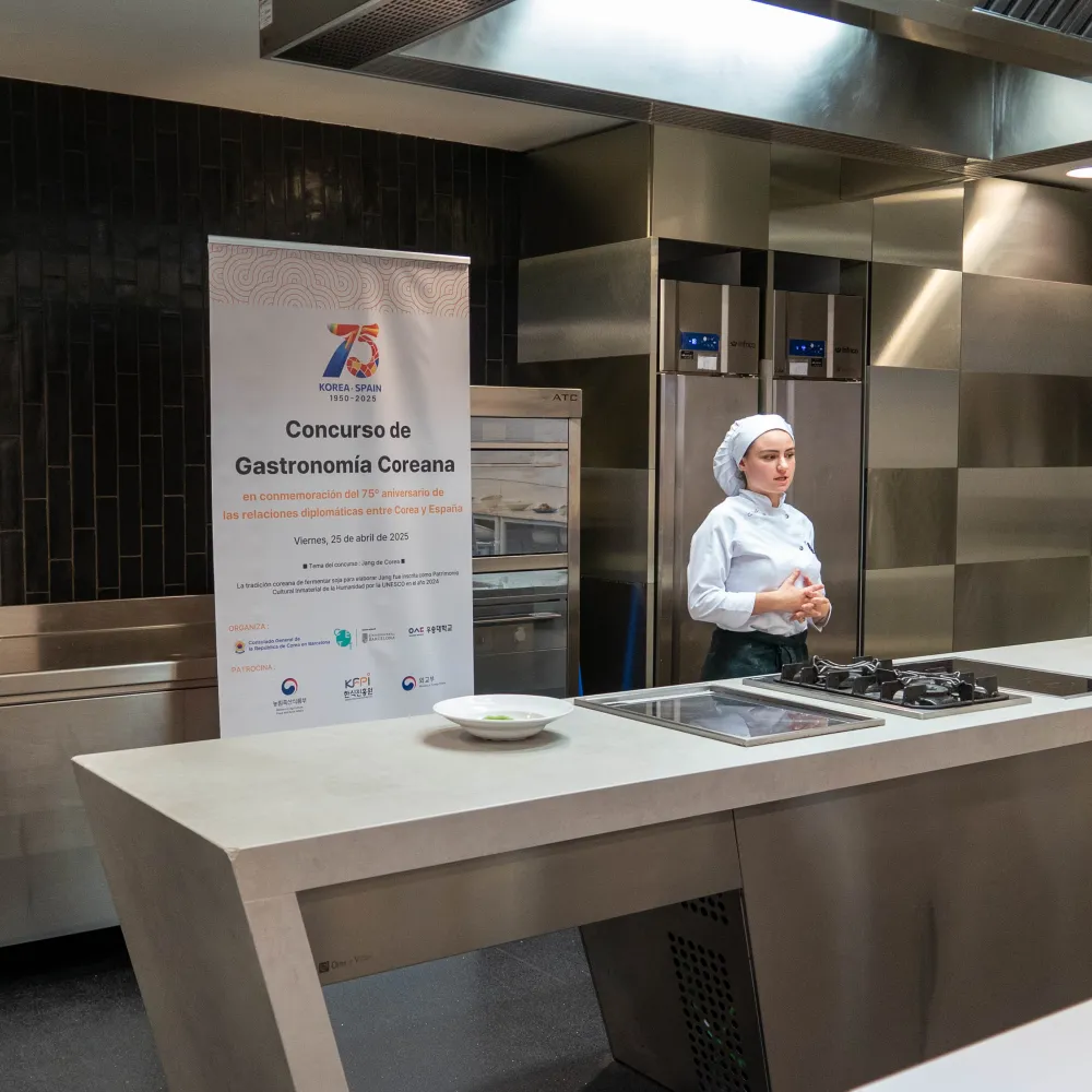 Una alumna presenta su plato al jurado en la cocina.