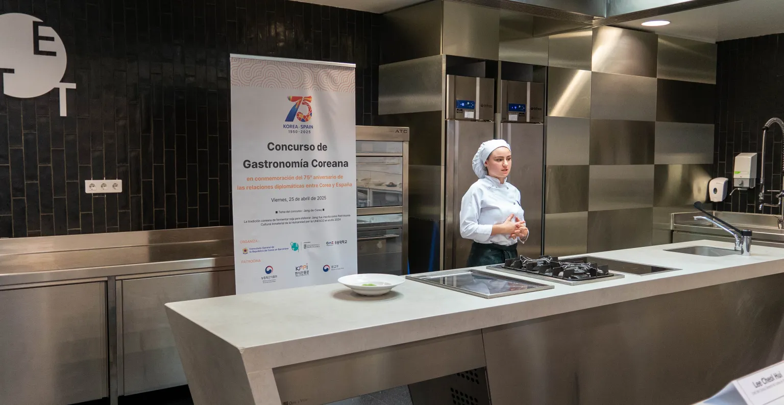 Una alumna presenta su plato al jurado en la cocina.