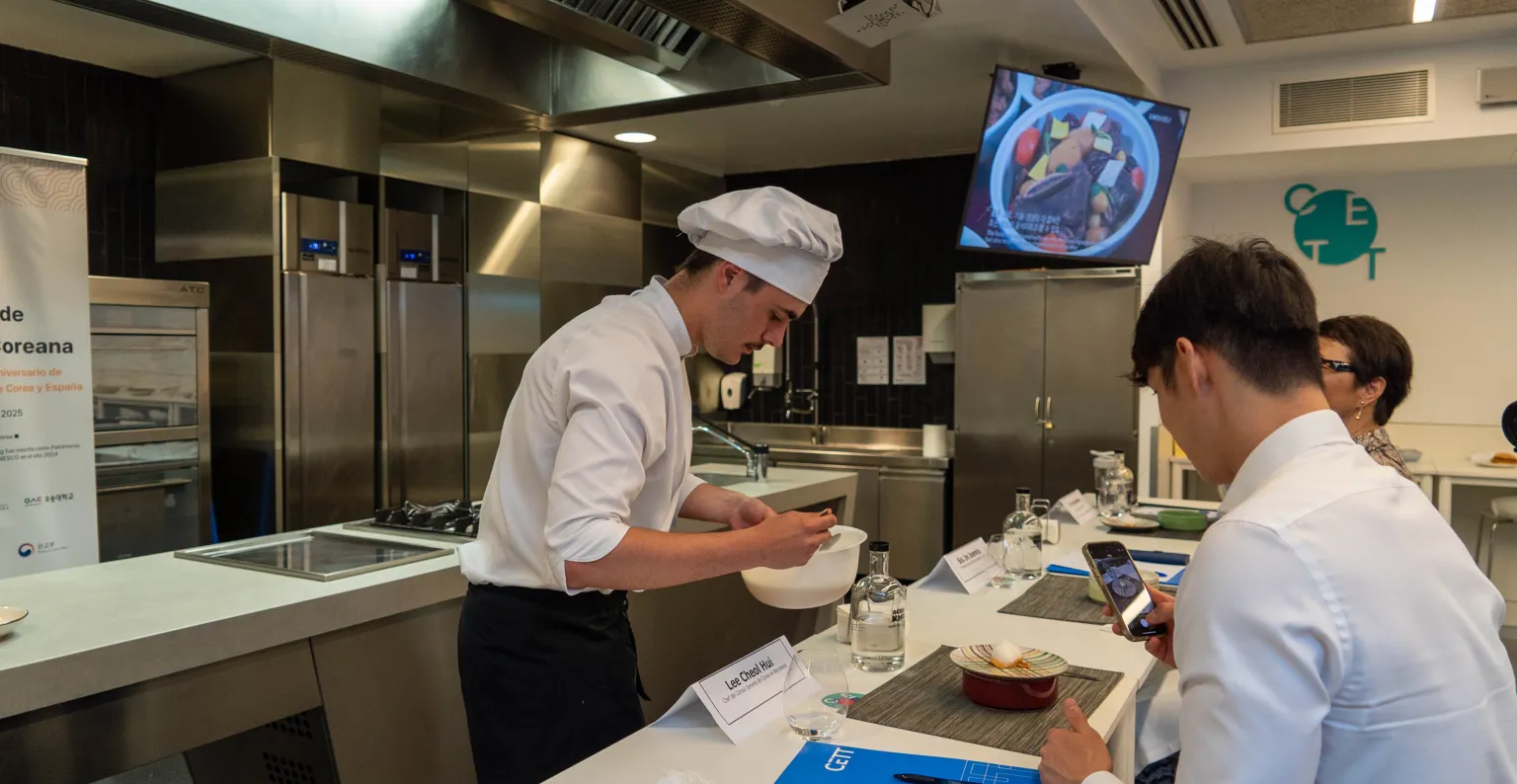 Un alumno presenta su plato al jurado en la cocina.